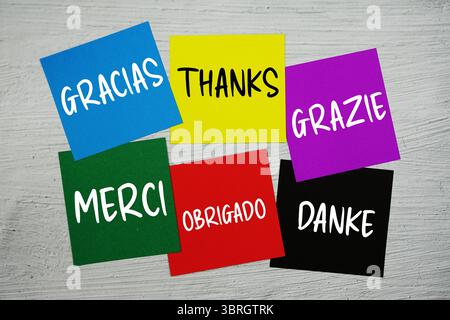 Grazie in diverse lingue testo su stick note su sfondo concreto Foto Stock