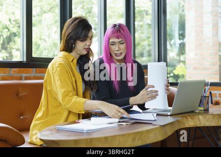 LGBTQ+ transgender uomo bellissimo autentico Specialista con capelli rosa e trans non binari che lavorano insieme Design nel team creativo del luogo di lavoro W Foto Stock