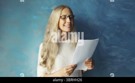 Lavoratrice professionista caucasica matura in occhiali da vista mentre lavora con documenti cartacei a casa o in ufficio Foto Stock