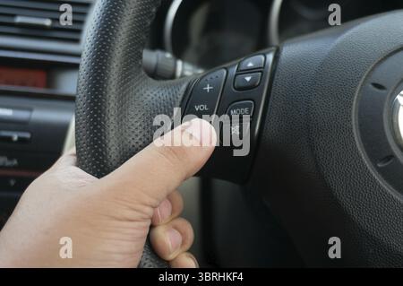 Uomo che guida le mani che preme il pulsante sul volante nella messa a fuoco selettiva della vettura. concetto di guida sicura Foto Stock