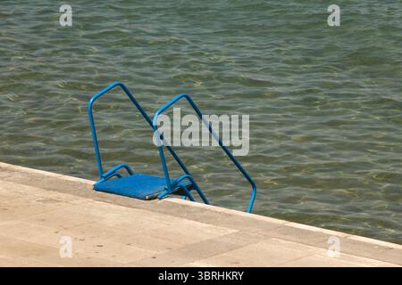 Una scala di metallo blu che porta giù verso il mare, da vicino presa Foto Stock