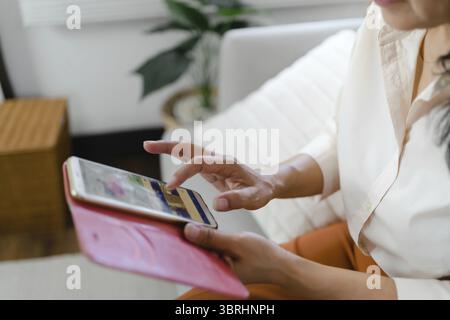 Donna asiatica di mezza età che tiene il telefono cellulare. donna anziana con smartphone. donna anziana che utilizza lo smartphone a casa con il concetto di tecnologia Foto Stock