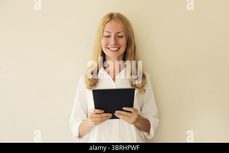 Ritratto di una giovane donna caucasica felice sorridente dipendente con un tablet digitale o una cartella con documenti in ufficio Foto Stock