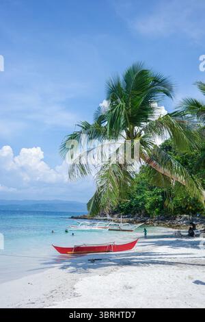 Una splendida vista costiera della remota spiaggia di sabbia bianca con palme e barche tradizionali nelle Filippine. Una vita isolana rilassata di Palawan Foto Stock