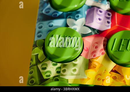 Tyumen, Russia - 8 luglio 2025: Il blocco Lego di costruzione verde si trova su uno sfondo colorato con disegni giocosi Foto Stock