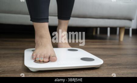 Piedi in piedi su bilance elettroniche per il controllo del peso. Strumento di misurazione in chilogrammi per il controllo della dieta Foto Stock
