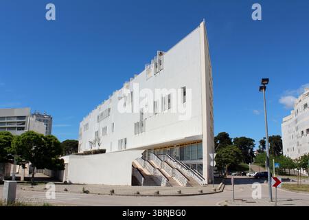 Un edificio bianco contemporaneo con linee nette e angolari e finestre geometriche si innalza su un cielo blu vivido, esemplificando il moderno Foto Stock