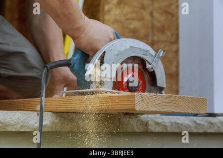 Carpenter utilizzando una sega circolare per la trave di legno un nuovo home progetto constructiion Foto Stock