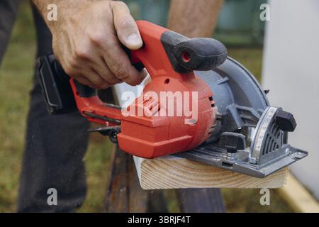 Lavoratore appaltatore che costruisce usando sega circolare manuale per tagliare le assi su un nuovo progetto di costruzione domestica Foto Stock