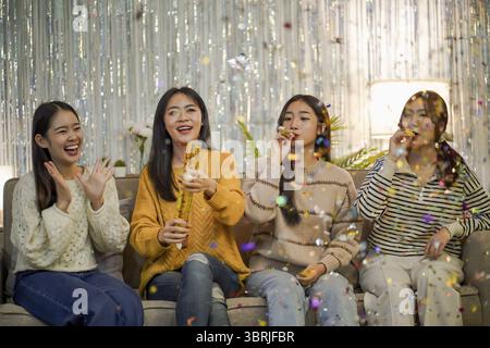 Amici allegri che si divertono con la festa di compleanno a casa. Amici asiatici che festeggiano la festa di Natale o di Capodanno Foto Stock