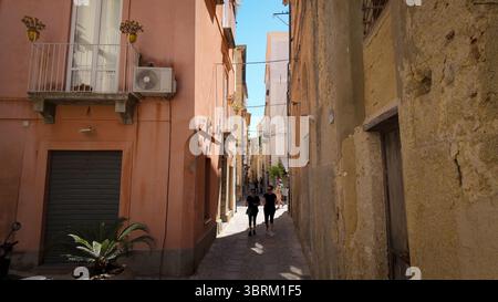TROPEA, ITALIA - 2 GIUGNO 2025 - due turisti che camminano in una tipica stradina di Tropea, Calabria, una popolare meta turistica del sud Italia Foto Stock