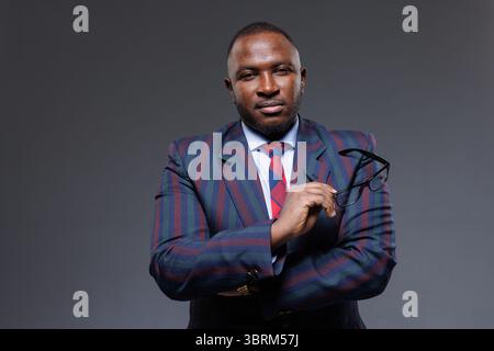 Ritratto di un uomo d'affari africano in elegante abito con occhiali, che mostra fiducia e leadership negli affari Foto Stock