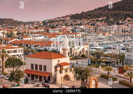 28 aprile 2025, Cesme, Turkiye: Vista aerea del porticciolo durante l'ora d'oro, con case tradizionali, moschea e barche Foto Stock