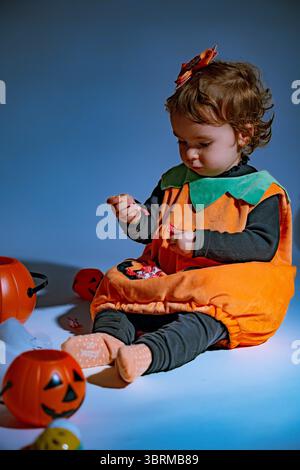 Bambina che indossa il costume di zucca con caramelle di halloween Foto Stock