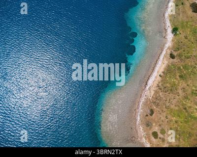 Prospettiva aerea mozzafiato che cattura la bellezza serena di una costa incontaminata, dove le acque cristalline turchesi accarezzano dolcemente la riva Foto Stock
