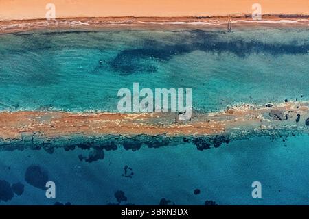 Splendida vista aerea che mostra le vibranti acque turchesi che incontrano una costa sabbiosa. Le texture e i colori naturali creano un'affascinante scena costiera Foto Stock