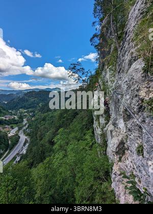 Scalatore che sale per Koschlak Klettersteig tramite la ferrata nelle Alpi austriache su pareti rocciose sicure. Foto Stock