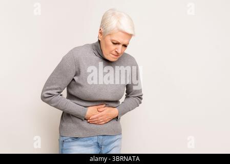 Infelice donna senior holding dello stomaco, che soffrono di dolore addominale Foto Stock