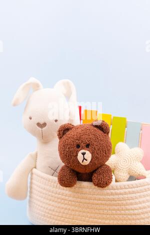 Sfondo astratto dei giocattoli per bambini. Morbidi giocattoli di peluche e giocattoli educativi in legno in una custodia bianca su sfondo azzurro. Vista frontale Foto Stock