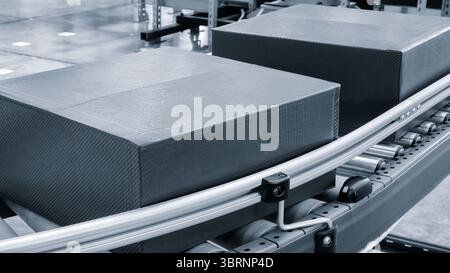 Scatole di cartone sul nastro trasportatore del moderno centro logistico di distribuzione, sfondo del concetto logistico di consegna tono blu Foto Stock