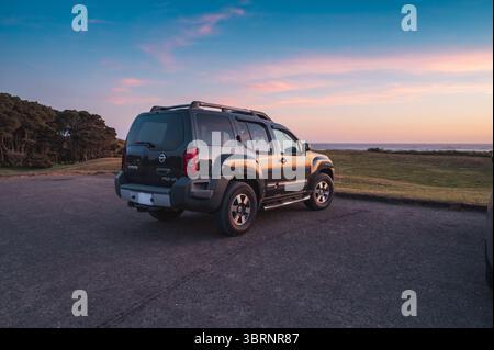 Una Nissan Xterra nera è parcheggiata vicino all'oceano al tramonto. Foto Stock