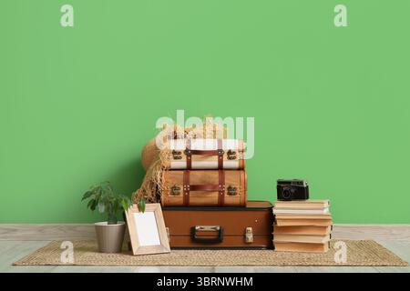 Libri e diverse valigie vintage vicino al muro verde in camera Foto Stock