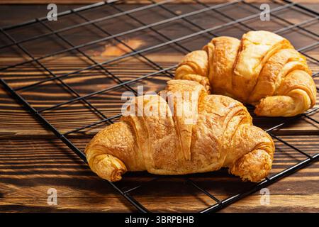 Croissant appena sfornati su un vassoio refrigerante con fondo in legno Foto Stock