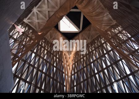 Un vasto e artistico interno architettonico con intricati motivi a griglia in legno e lucernario, che creano spettacolari effetti di luce ed ombra. Foto Stock