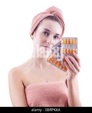 Donna sorridente in possesso di integratori di bellezza e benessere blister, con asciugamano sulla testa e sul corpo. Cura di sé, salute, routine di bellezza quotidiana, pelle pulita Foto Stock