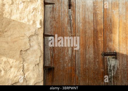 vecchia porta in legno su pareti di fango con effetto calce, vecchie case cittadine con porte e finestre colorate Foto Stock