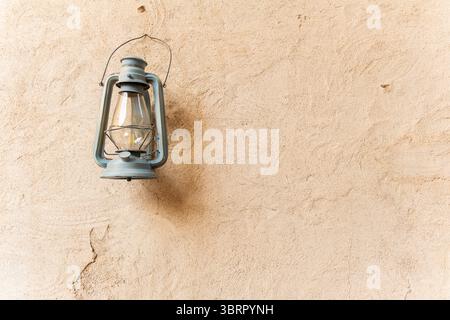 Lanterna antica appesa su sfondo vecchio muro, con spazio vuoto per testo o contenuto, sfondo estetico in gesso con lanterna in vetro Foto Stock