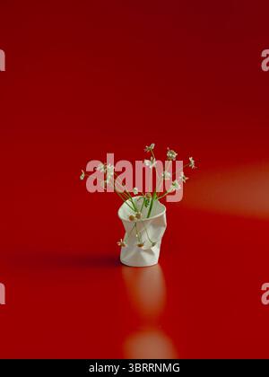 Disposizione floreale minima in tazza bianca schiacciata su sfondo rosso Foto Stock