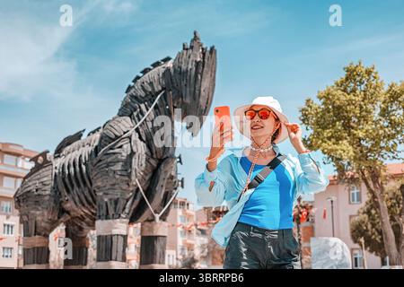 6 maggio 2025, Canakkale, Turchia: Turista femminile che scatta selfie con lo smartphone di fronte al cavallo di Troia Foto Stock