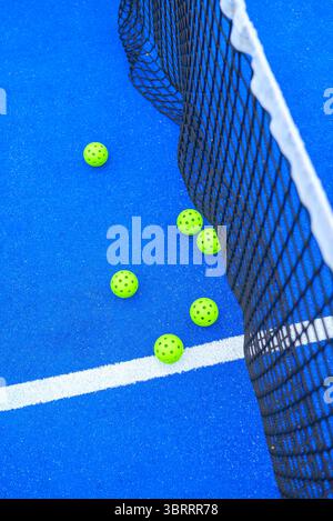 vista dall'alto di un angolo del campo da tennis in padel blu con rete e palle gialle Foto Stock