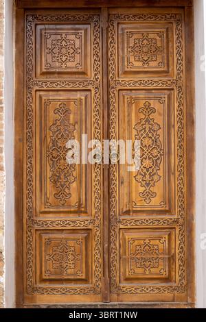 Porta in legno splendidamente intagliato in legno di noce, che mostra la tradizionale maestria artigianale e intricati motivi decorativi. Foto Stock