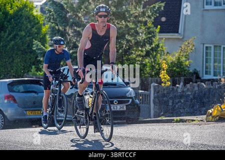 Swansea Ironman si arrampica sulle colline nel caldo mattutino, partecipando alla famosa gara di triathlon che si snoda oltre i Giardini Thistleboon sulla sezione Mumbles del percorso di Swansea. Foto Stock