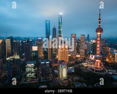 Shanghai, Cina - 21 giugno 2025: Veduta aerea della Oriental Pearl Tower che attraversa il crepuscolo, giustapposta allo skyline illuminato dei moderni grattacieli. Foto Stock