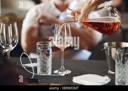 Scuola sommelier. Un cameriere professionista che versa il vino nel decanter ai bicchieri durante la formazione sulle bevande alcoliche per il personale. Vino cieco Foto Stock