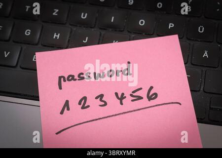 Sicherheitsrisiko auf dem Schreibtisch: Ein Zettel mit dem unsicheren Passwort 123456 liegt offen auf einem laptop, ein klassisches Beispiel für fahrlässigen Umgang mit sensiblen Zugangsdaten. *** Rischio di sicurezza sulla scrivania: Un pezzo di carta con la password non sicura 123456 aperta su un laptop è un classico esempio di gestione negligente dei dati di accesso sensibili. Nordrhein-Westfalen Deutschland, Germania GMS19548 Foto Stock