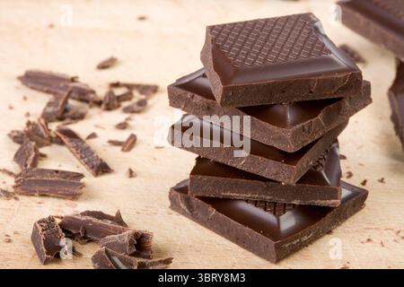 Pezzi di cioccolato impilati su un tagliere di legno Foto Stock