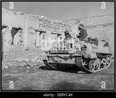 WW2 North Africa Vickers-Armstrong Bren / Universal Carrier con soldati dell'esercito britannico che passano un deposito di provviste dell'esercito bombardato Tunisia Nord Africa 1940 Foto Stock