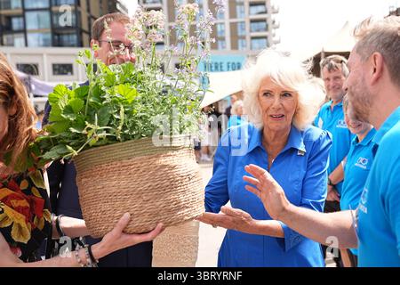 La Regina Camilla, Patrona della Battersea Dogs and Cats Home, viene presentata con un regalo durante una visita per svelare la Royal Horticultural Society (RHS) e BBC radio 2 'Dog Garden', progettato da Monty Don, installato di recente nel centro di Londra dell'ente di beneficenza, presso la struttura di beneficenza nel sud di Londra. Data foto: Lunedì 14 luglio 2025. Foto Stock