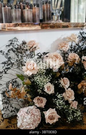Un elegante allestimento floreale con rose e candele crea un ambiente lussuoso, perfetto per ambienti romantici e arredi sofisticati. Foto Stock