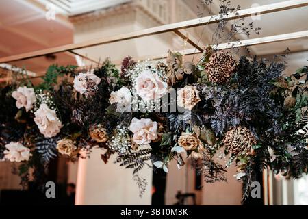 Elegante installazione floreale con rose e felci, per un ambiente interno di lusso. perfetto per eventi eleganti e feste sofisticate Foto Stock