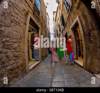 Spalato, Croazia - 8 settembre 2023: Tre donne fanno shopping in una strada stretta. Una donna sta entrando in un negozio con una borsa della spesa, mentre le altre una Foto Stock