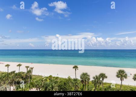 Vista aerea delle acque turchesi che incontrano la spiaggia di sabbia bianca circondata da palme sotto un cielo azzurro, Miami Beach, Florida, Stati Uniti. Foto Stock