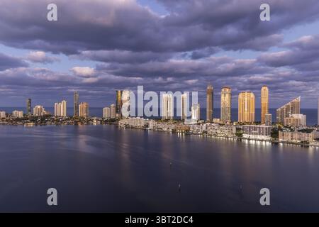 Vista aerea dello splendido skyline che si riflette nell'acqua, con gli edifici torreggianti di Sunny Isles Beach illuminati contro il cielo crepuscolo, Sunny Isles Beach, Florida, Stati Uniti. Foto Stock