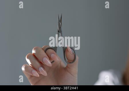 Primo piano di forbici professionali per manicure che lavorano su eleganti unghie color beige nel salone Foto Stock
