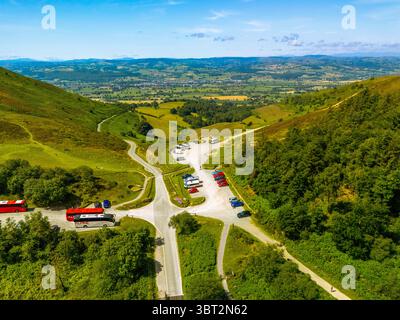 Una vista aerea mostra diversi furgoni e auto parcheggiati in un sacco vicino a una collina erbosa, probabilmente per i visitatori di godersi il paesaggio naturale e i sentieri escursionistici Foto Stock
