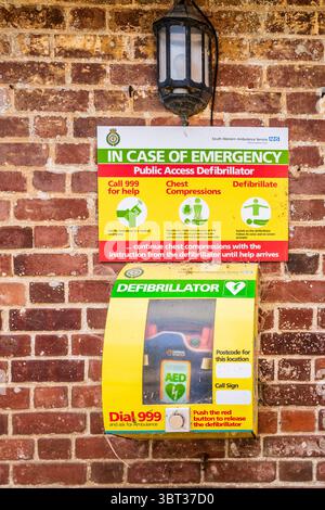 Defibrillatore ad accesso pubblico sul muro in mattoni rustici in un villaggio rurale del Dorset. Foto Stock